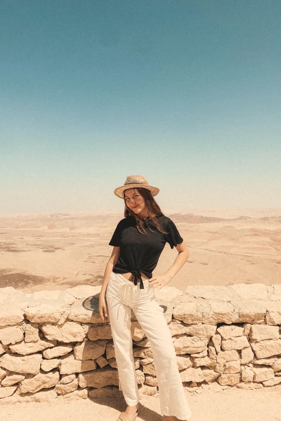 אלונה עומדת על שפת מכתש במדבר